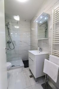 a white bathroom with a sink and a shower at Luce Gold Apartment in Zadar