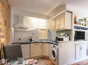 a kitchen with white cabinets and a dishwasher at La Ritournelle in Sarlat-la-Canéda