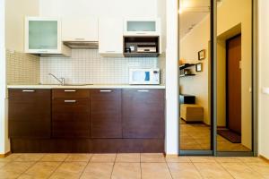 a kitchen with wooden cabinets and a microwave at Daukanto Sun Apartment in Palanga