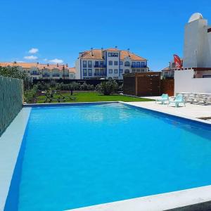 uma grande piscina azul com edifícios ao fundo em Alex Surf Hostel no Baleal