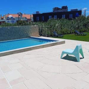 una silla azul sentada junto a una piscina en Alex Surf Hostel, en Baleal