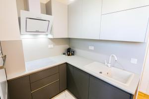 a kitchen with white cabinets and a sink at Luce Gold Apartment in Zadar