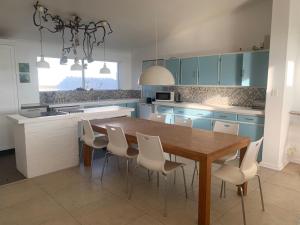 a kitchen with a wooden table and white chairs at Witbaai Beach House in Britannia Bay