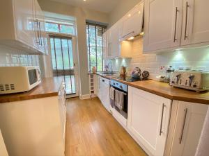 cocina con armarios blancos y suelo de madera en Old Abbey Cottage, en North Berwick