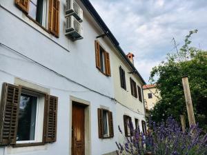 a white building with wooden windows and purple flowers at Apartments Šik 2 in Koper