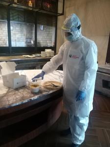 a person in a white suit preparing food in a kitchen at Ramada Encore Jalandhar in Jalandhar