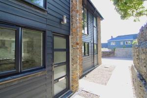 a house with black siding and windows on it at Oliver's Yard in Helston