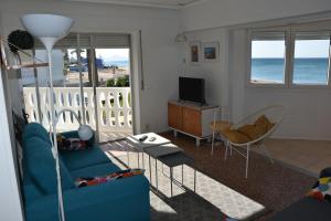 a living room with a blue couch and a television at Holiday Beach Apartment in Denia
