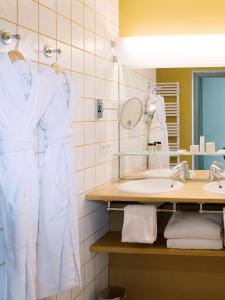 a bathroom with white robes and a sink at Hôtel de l'Image in Saint-Rémy-de-Provence