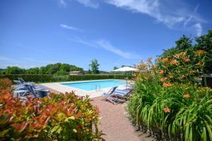 a pool with chairs and an umbrella and some plants at Agriturismo Corte dei Fiori in Caprino Veronese