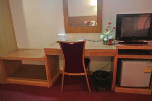a desk with a television and a chair in a room at Chaikana Thani Hotel in Phatthalung