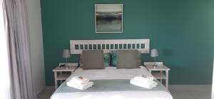 a blue bedroom with a bed with towels on it at OCEAN VIEW GUEST HOUSE in Jeffreys Bay