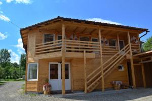 a log cabin with a porch and a deck at Pensiunea Lore&Sara in Satu Şugatag