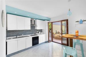 a kitchen with white cabinets and a wooden table at Villa Capo D'Arco in Massa Lubrense