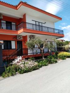 a house with a balcony and flowers in front of it at Deaspoina Apartments in Nea Roda