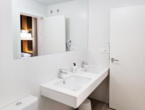 
a white sink sitting under a mirror in a bathroom at Broz Hostel in Granada
