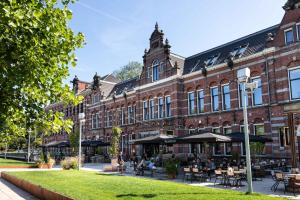 a large brick building with tables and chairs in front of it at Conscious Hotel Westerpark in Amsterdam