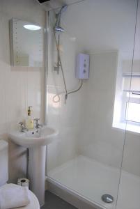 a white bathroom with a sink and a shower at Snowdon Cottage 2 in Llanrug