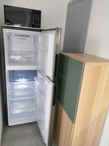 un frigorifero vuoto con porta aperta e forno a microonde di Appart' O bernai a Obernai