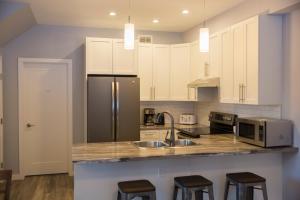 cocina con armarios blancos y nevera de acero inoxidable en Downtown Whitehorse 4 bedrooms deluxe condo, en Whitehorse