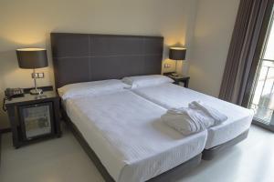 a bedroom with a large bed with white sheets and pillows at Hotel Real Balneario Carlos III in Trillo