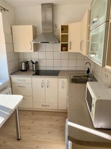 a kitchen with white cabinets and a sink at Centro Apartamentai in Zarasai