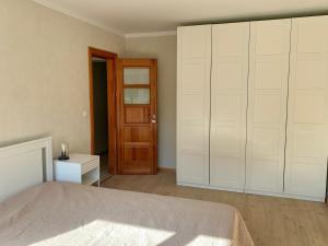 1 dormitorio con 1 cama y puerta de madera en Centro Apartamentai, en Zarasai