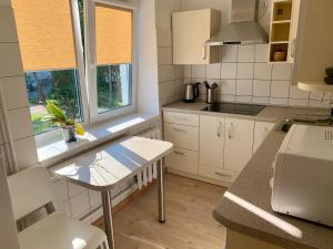 a kitchen with white cabinets and a table and a window at Centro Apartamentai in Zarasai