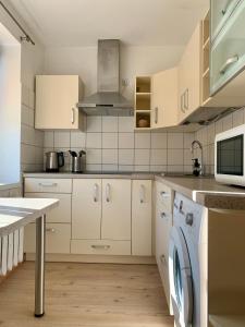 a kitchen with white cabinets and a washer at Centro Apartamentai in Zarasai