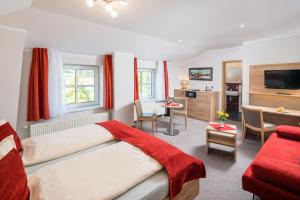Un dormitorio con una cama con una manta roja. en Hotel Rabennest en Rabenau