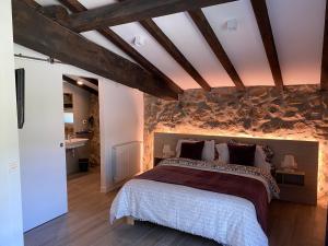 1 dormitorio con 1 cama grande y pared de piedra en Casa Rural Martiamuno Landetxea, en Zumárraga