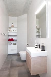 a white bathroom with a toilet and a sink at L'appartement in Reconvilier