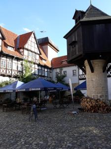 einen Innenhof mit Tischen, blauen Sonnenschirmen und Gebäuden in der Unterkunft Adelshof Quedlinburg in Quedlinburg