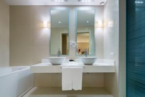 un bagno con 2 lavandini, uno specchio e una vasca di Base Hotel a Noventa di Piave