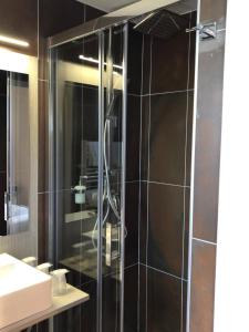 W łazience znajduje się prysznic ze szklanymi drzwiami. w obiekcie Hôtel Du Viaduc w mieście Tarascon