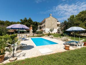 a swimming pool with two umbrellas and a house at Apartman Šušnjić in Poreč