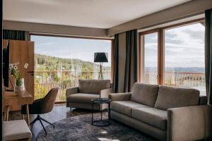 a living room with a couch and a large window at Radisson Hotel Szklarska Poręba in Szklarska Poręba