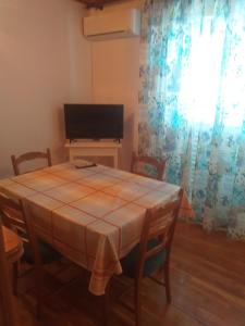 a dining room with a table with chairs and a television at Guest House Silvia in Rab
