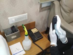a person in white gloves is talking on a telephone at Hotel Atishay in Bhopal