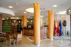un vestíbulo de un hotel con columnas, mesas y sillas en Hotel Los Habaneros en Cartagena