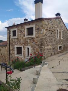 un edificio de piedra con una torre encima en La Laguna, en Hinojosa de la Sierra