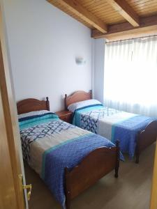 two beds in a room with a window at La Laguna in Hinojosa de la Sierra