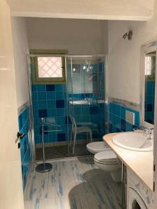 - une salle de bains carrelée de bleu avec 2 toilettes et un lavabo dans l'établissement Visit San Teodoro, à San Teodoro