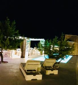 a group of lounge chairs and a pool at night at Milo Milo Suites in Mandrakia