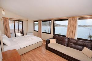 a bedroom with a bed and a couch and windows at Kerman Hotel in Cesme +65 photos
