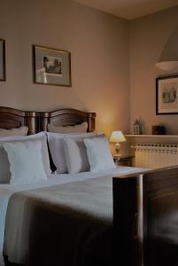 1 dormitorio con 1 cama grande con almohadas blancas en B&B Casa Margot, en Neive