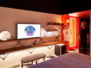 a woman standing in a bedroom with a tv on a wall at Mama Shelter Toulouse in Toulouse