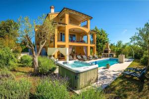 a house with a hot tub in the yard at Spacious holiday house - pool / jacuzzi / sauna / playground / 8+2 in Rakalj