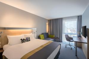 ギュータースローにあるHoliday Inn Express Gütersloh, an IHG Hotelのベッドとデスクが備わるホテルルームです。