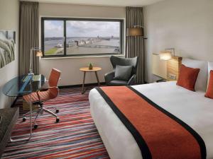a hotel room with a bed and a desk and a window at Mövenpick Hotel Amsterdam City Centre in Amsterdam